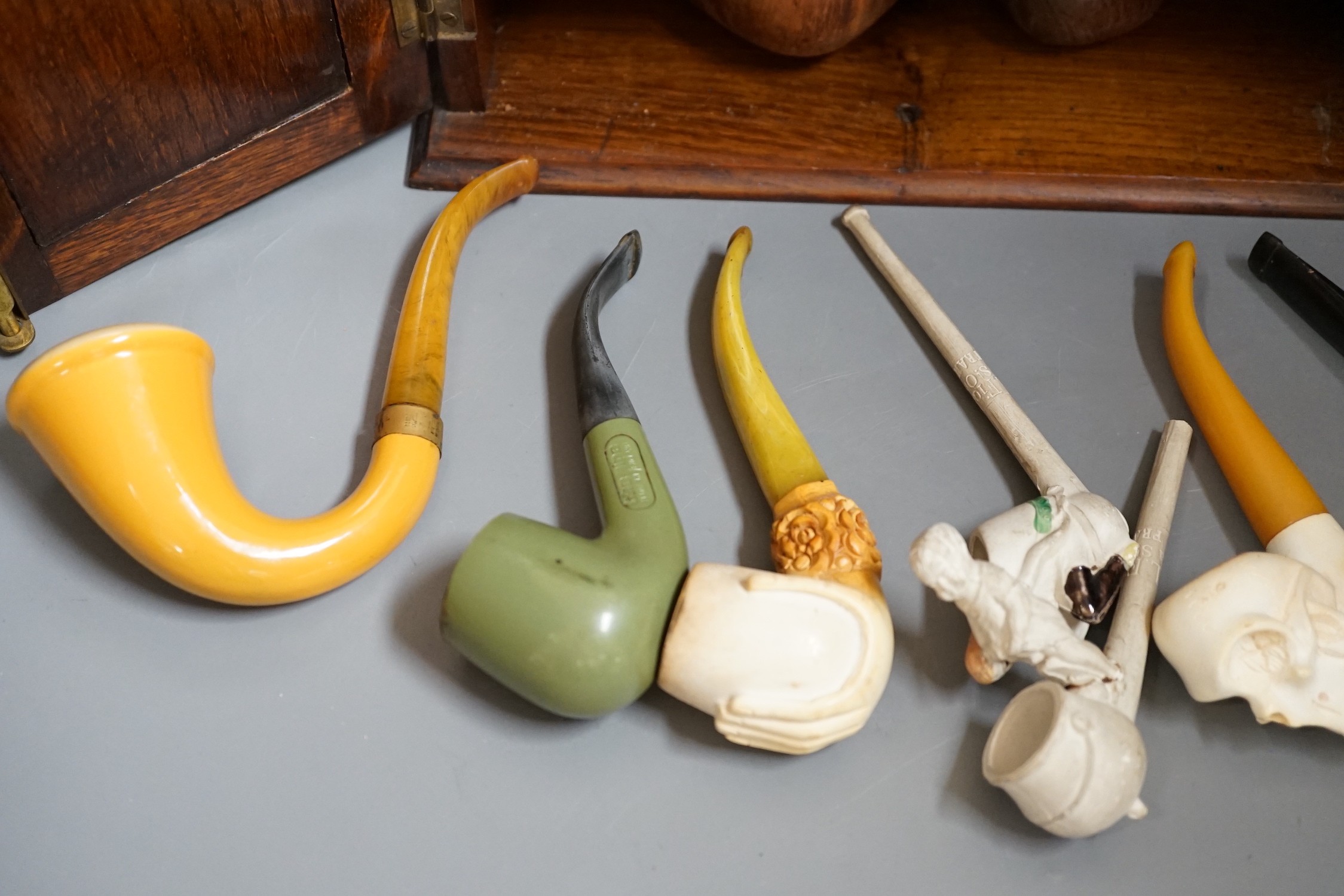 A carved smoker’s cabinet containing Meerschaum and other pipes and a tobacco jar, cabinet 25cm high